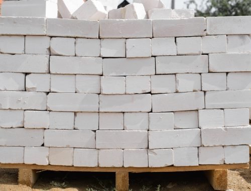 Construction site, pile of gray bricks on wooden pallet outdoors, close-up. Material for building construction, industry concept