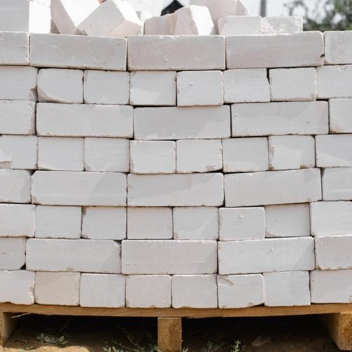 Construction site, pile of gray bricks on wooden pallet outdoors, close-up. Material for building construction, industry concept